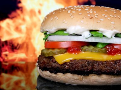 A cheeseburger beside a sleek limousine, symbolizing the collision of National Cheeseburger Day deals and Chicago's luxury car services in 2023.